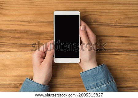 Overhead photo of cellphone in hands isolated on the wooden backdrop