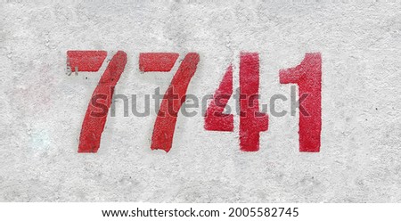 Red Number 7741 on the white wall. Spray paint. Number seven thousand seven hundred and forty one.