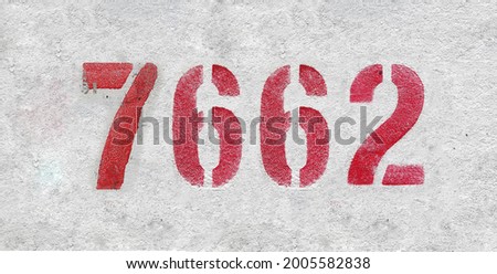 Red Number 7662 on the white wall. Spray paint. Number seven thousand six hundred and sixty two.