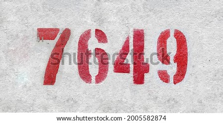 Red Number 7649 on the white wall. Spray paint. Number seven thousand six hundred forty nine.