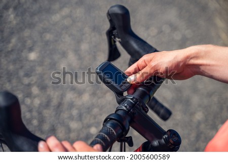 Close-up of a woman cyclist's hands turning on her bike's Gps Navigator to start a burp in the mountains. Royalty-Free Stock Photo #2005600589