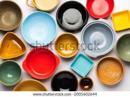 Collection of empty colorful ceramic bowls. Group of utensils captured from above, top view, flat lay against white background