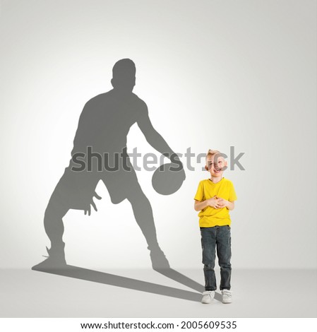 Dreams about big and famous future. Conceptual image with little boy and shadow of male basketball player on light gray background. Childhood, dreams, imagination, education concept. Looks happy