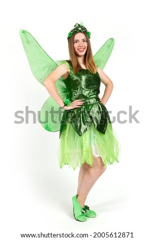 A young girl dressed as a forest fairy with wings in the studio on a white background.