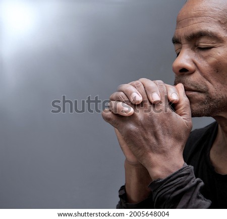 man praying to god with hands together Caribbean man praying stock photo 