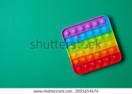 Rainbow silicone sensory antistress pop it toy on green background. Top view. Space for text.