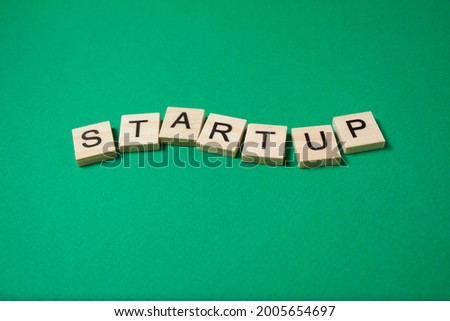 Business Startup Concept. Word Startup made of wooden letters on a green background