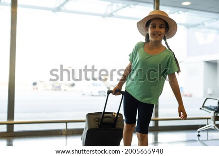 beautiful little girl holding passport and boarding pass at airport