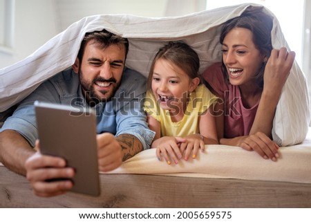 People and family concept - happy mother, father and little daughter with tablet pc computer in bed  in the morning.