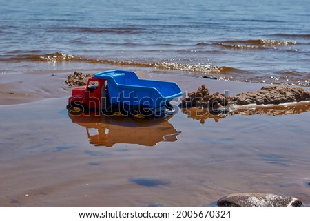 Children's toy bright blue plastic dump truck on the sandy beach of the sea . High quality photo Royalty-Free Stock Photo #2005670324
