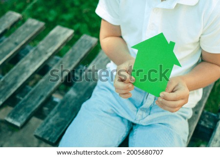 Green paper house in the hands of a child. Concept of ecological houses. outdoors. High quality photo
