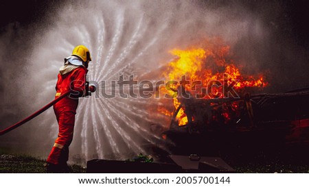 Firefighters, Firemen spraying high pressure water or suitable extinguishing agents to fire with copy space . Royalty-Free Stock Photo #2005700144