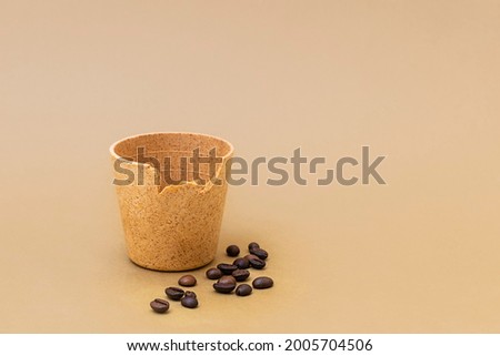 Coffee or tea cup with roasted coffee beans on beige background. Edible cups as new zero waste trend Royalty-Free Stock Photo #2005704506