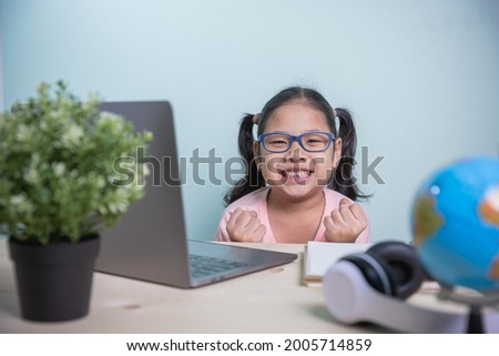 Asian kids girls wearing glasses smile happily looking at a camera. express joy success answer to online lessons from teachers. learning from home in the room personal. Concept learning online.
