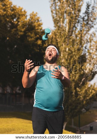 
a fat boy throwing a dumbbell in a park