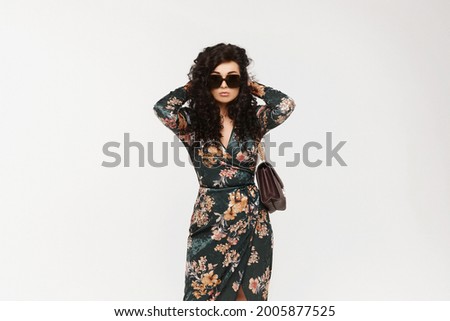 Fashion photo of a beautiful young woman in a pretty dress with flowers posing over white background.
