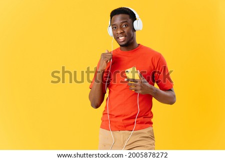 man with headphones listening to music and technology yellow background