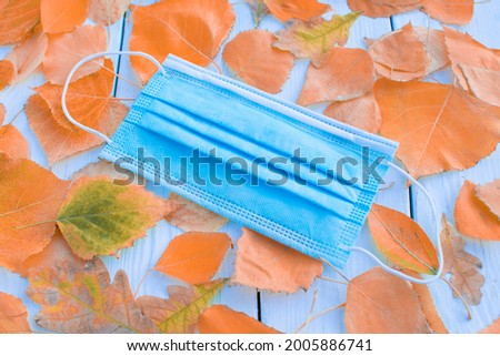 Medical mask autumn on a background of fall leaves. Concept covid, respiratory disease, protection