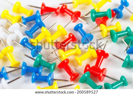 Multicolored office pushpins on white desktop close up