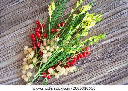 Bouquet of wildflowers with currant berries on a wooden background. Bright yellow flowers.