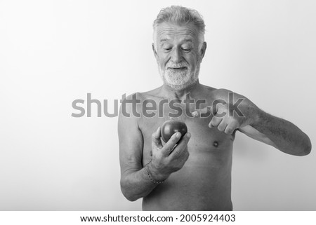 Studio shot of handsome senior bearded man shirtless against white background in black and white