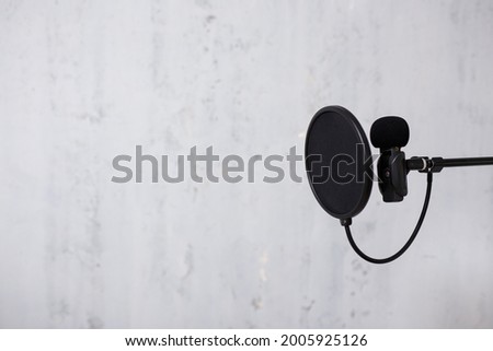 podcast, sound recording and blogging concept - microphone and pop filter over grey background with copy space