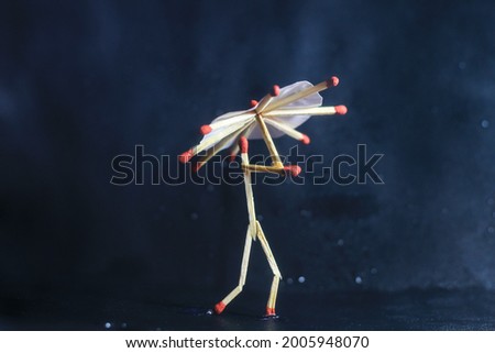 A matchstick man with a matchstick umbrella in the rain. Raining concept. Matchstick art photography used matchsticks to create the character. Royalty-Free Stock Photo #2005948070