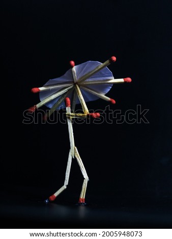 A matchstick man with a matchstick umbrella in the rain. Raining concept. Matchstick art photography used matchsticks to create the character. Royalty-Free Stock Photo #2005948073