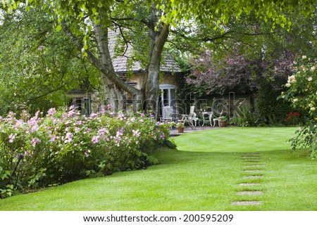 Cotswold Cottage Garden, with small patio outside and stoned path leading to it. Royalty-Free Stock Photo #200595209