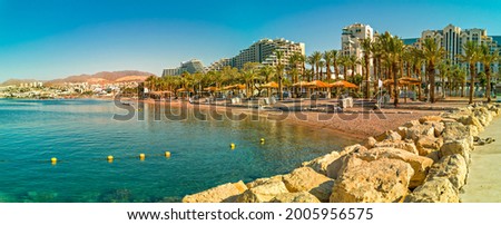 Swimming morning at sandy beach of the Red Sea, panoramic view from central stone walking pier and promenade in Eilat - famous tourist resort city in Israel  Royalty-Free Stock Photo #2005956575