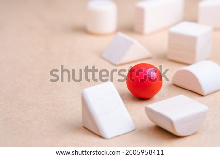 A wooden red ball in a group of other geometric wood toys as business strategy, position in the market, define the target Royalty-Free Stock Photo #2005958411
