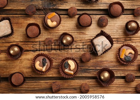 Different delicious chocolate candies on wooden table, flat lay