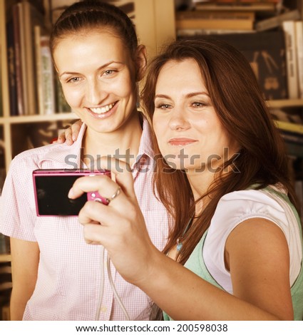 two cute girlfriends taking photo of themselves in library