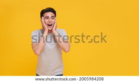 Surprised and Shocked asian man covering mouth with hands isolated on bright yellow background.