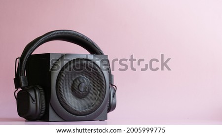 Black audio speaker and headphones with ambryushores on a pink background. Pop music concept. Free space for text, inscription and labels. Close-up Royalty-Free Stock Photo #2005999775