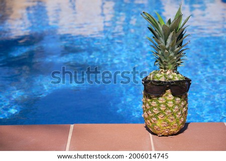 Pineapple with sunglasses at the edge of a swimming pool,Healthy holiday concept, Spain.