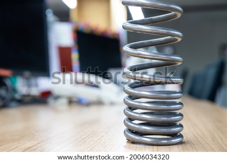 Metal spring on the brown wooden table, coil spring wire on the desk.