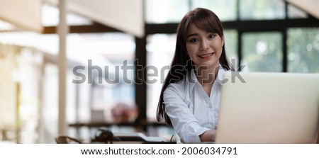 Portrait of a cheerful businesswoman sitting at the table in office and looking at camera
