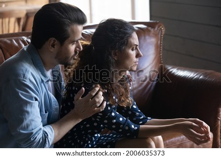 Compassionate husband giving comfort and support to upset wife, holding shoulders, speaking expressing empathy. Man feeling guilty, asking girlfriend to forgive. Relationship, compassion concept