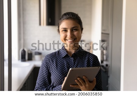 Portrait of happy Indian female customer using app service on tablet for online learning, shopping and ordering, electronic payment, remote business work, looking at camera, smiling, Head shot