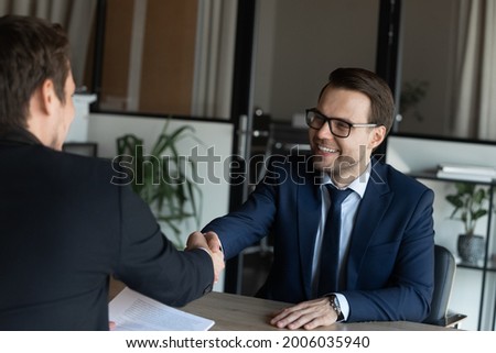 Employer hiring happy candidate after successful interview, giving handshake. Business partners shaking hands in office after negotiations, closing deal. Boss congratulating employee on promotion Royalty-Free Stock Photo #2006035940