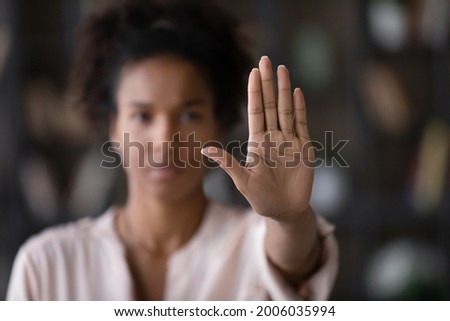Close up of African American woman showing stop gesture with hand blurred background, young female protesting against domestic violence and abuse, bullying, saying no to gender discrimination Royalty-Free Stock Photo #2006035994