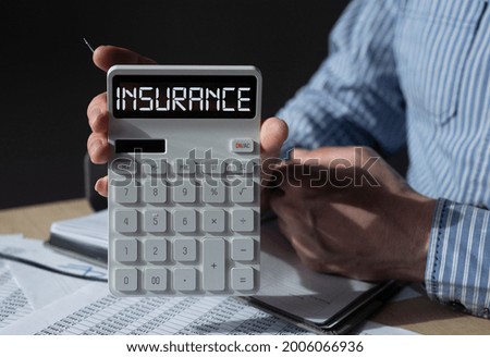 Insurance word on calculator in hands of agent.
