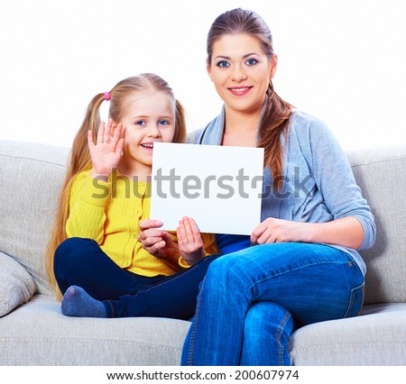 Smiling woman with girl holding blank card. Sitting on sofa.
