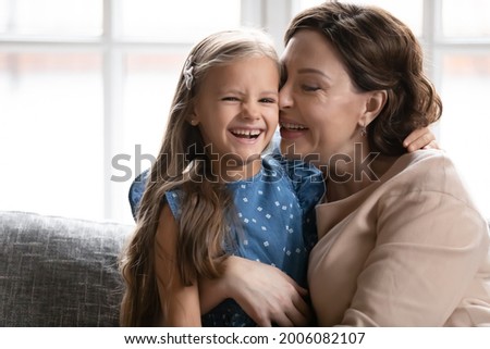 Portrait of loving middle-aged Caucasian grandmother hug cuddle little granddaughter show care and support. Happy old granny embrace smiling cute small girl child enjoy family time together.