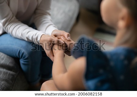 Crop close up of loving young mother hold small teen daughter hands show love and care in relations. Attentive mom caress comfort support little girl child. Family unity, motherhood concept. Royalty-Free Stock Photo #2006082158