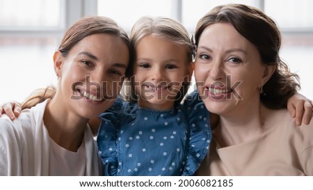 Headshot portrait of happy three generations of women hug cuddle show family unity and bonding support. Profile picture of smiling little girl with mother and grandmother embrace. Unity concept.