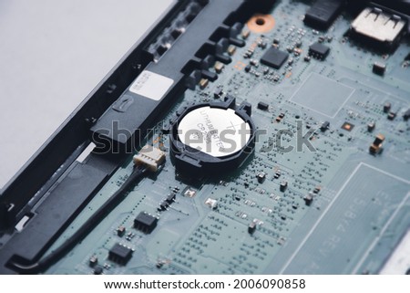 Button cell lithium battery CR2025 3V in cmos backup battery slot on the motherboard of laptop Royalty-Free Stock Photo #2006090858