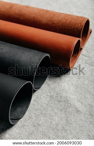 Rolls of black and red leather on grey background