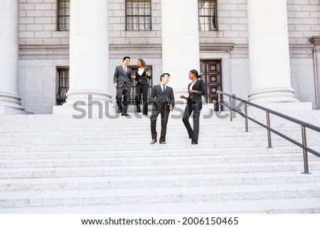 Four well dressed professionals walk down steps in discussion outside of a courthouse or municipal building.. Could be lawyers, business people etc. Royalty-Free Stock Photo #2006150465